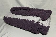 two purple and white crocheted bedspreads laying on top of each other