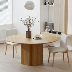 a round wooden table with white chairs around it