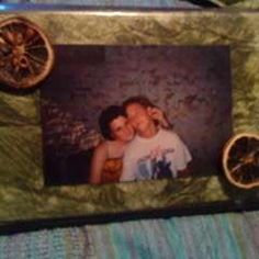 two people are kissing in front of some oranges and an old fashioned photo frame