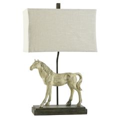 a white horse figurine next to a lamp on a wooden base with a linen shade