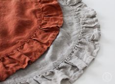 three pieces of clothing sitting on top of a white tablecloth covered in red and grey ruffles