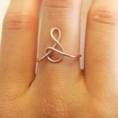 a woman's hand with a ring on it that is shaped like an infinite knot