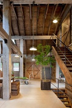 the inside of a building with wooden stairs and plants in pots on the ground below