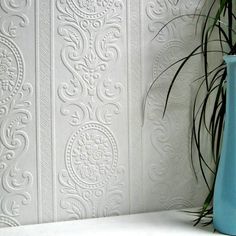 a blue vase sitting on top of a white shelf next to a potted plant