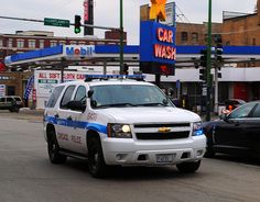 a police car is driving down the street in front of a car wash and gas station