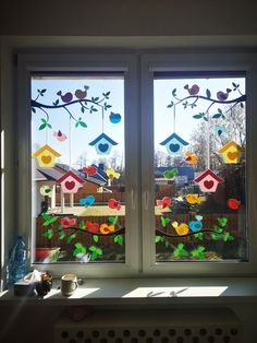 two windows with birds and birdhouses on them in front of a window sill