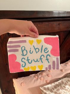 a person holding up a bible stuff bag on a bed with pink and yellow sheets