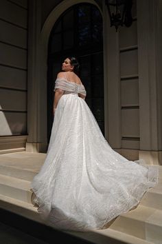 a woman in a white wedding dress standing on the steps with her back to the camera