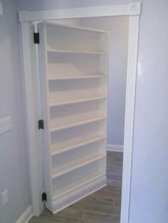 an empty white book shelf in the corner of a room