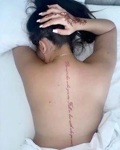 a woman laying in bed with her back turned to the camera and tattoos on her body