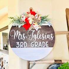 a wooden sign that says mrs tolesias 3rd grade hanging on the wall next to a potted plant