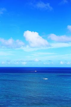 a boat is out in the ocean on a sunny day with blue sky and clouds