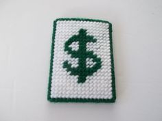 a white and green square with a cross stitched into the center, on a white surface