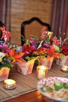 there are many small cups with flowers in them on the table next to some candles