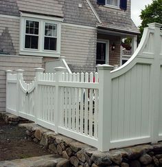 a white picket fence in front of a house with rocks on the ground next to it