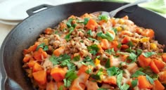 a skillet filled with meat and vegetables on top of a table