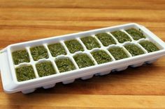 an ice tray filled with green food on top of a wooden table