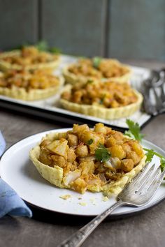 two white plates topped with food on top of a wooden table next to utensils