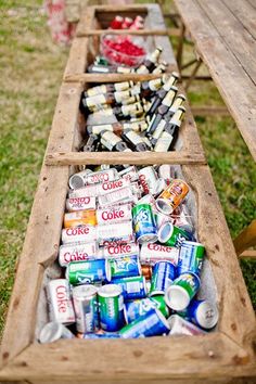 an old wooden wagon filled with cans and cans of soda on top of green grass