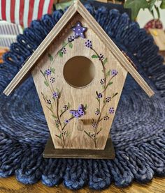 a wooden birdhouse with flowers painted on it's side sitting on a blue blanket