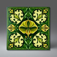 a green and yellow square tile with an ornate flower design on it's side