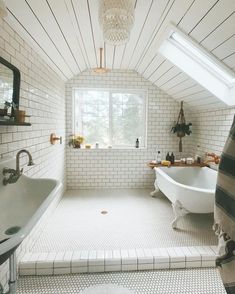 a bathroom with a tub, sink and window in the ceiling is white bricked walls