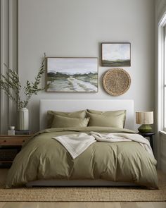 a bedroom with a large bed and two pictures on the wall above it, along with a wicker basket