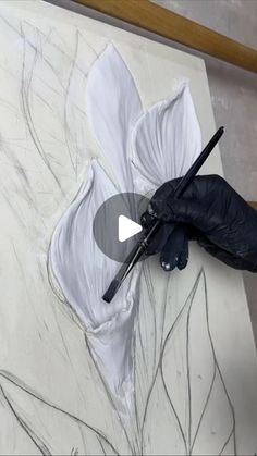 a person in black gloves is painting a flower