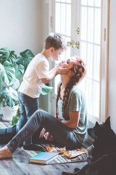 a woman sitting on the floor next to a little boy