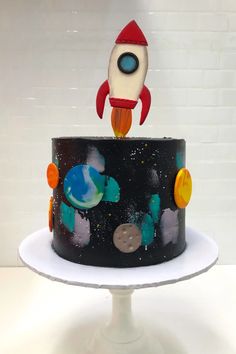 a cake decorated with an outer space theme and a rocket ship topper on it