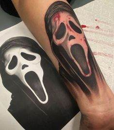 a person with a black and white tattoo on their arm wearing a ghost face mask