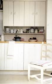 a kitchen with white cupboards and an old chair in the middle of the room