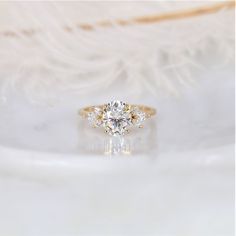 an engagement ring with three stones on top, sitting on a feathery surface in front of the camera