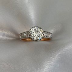 an old cut diamond ring on a white satin background with gold and silver bands around the band