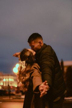 a man and woman standing next to each other in front of a building at night