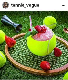 a green tennis ball with strawberries on it and other tennis balls surrounding the bowl