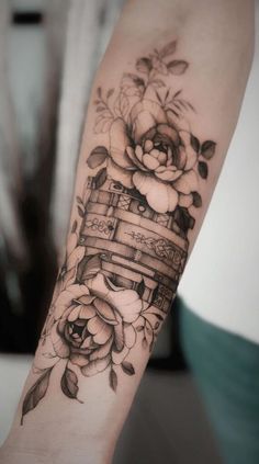 a woman's arm with flowers and a basket tattoo on her left arm, which is decorated with roses