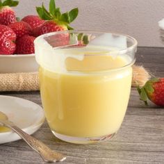 a glass full of liquid sitting on top of a table next to some strawberries