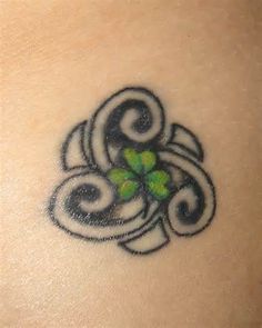 a tattoo on the back of a woman's shoulder with clovers in it