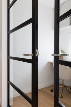 an open glass door in the middle of a room with a desk and chair next to it