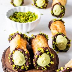 chocolate covered pastries with green sprinkles next to a bowl of pistachio