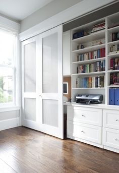 an empty room with white bookcases and wooden floors