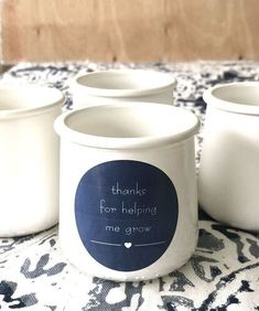 four white mugs sitting on top of a blue and white cloth covered tablecloth