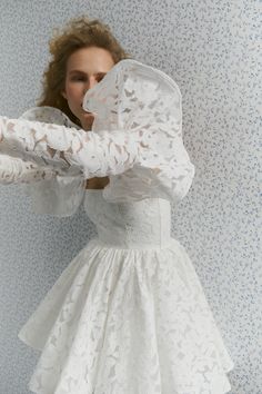 a woman in a white dress is posing for the camera with her hands on her face