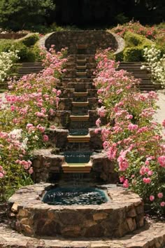 an outdoor fountain surrounded by pink flowers and stone steps leading up to the water feature