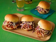 three pulled pork sliders with coleslaw slaw on a cutting board