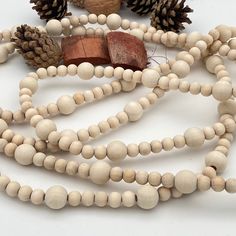 a wooden bead necklace with pine cones and other wood beads on it's side