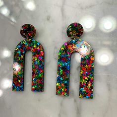 pair of multicolored earrings on marble counter top with circles and dots in the background