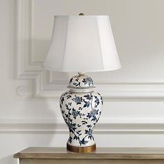 a blue and white vase sitting on top of a table next to a lamp