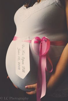 a pregnant woman is holding her belly with a pink ribbon around it's waist